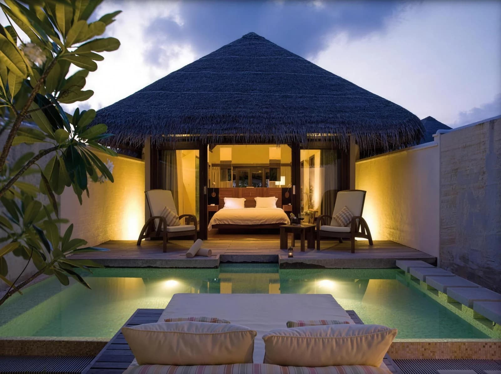 Island villa with private pool lit at dusk